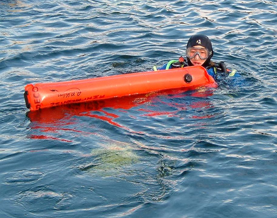 Diver left behind by boat rests at the surface holding surface marker buoy waiting for the dive boat to return for him