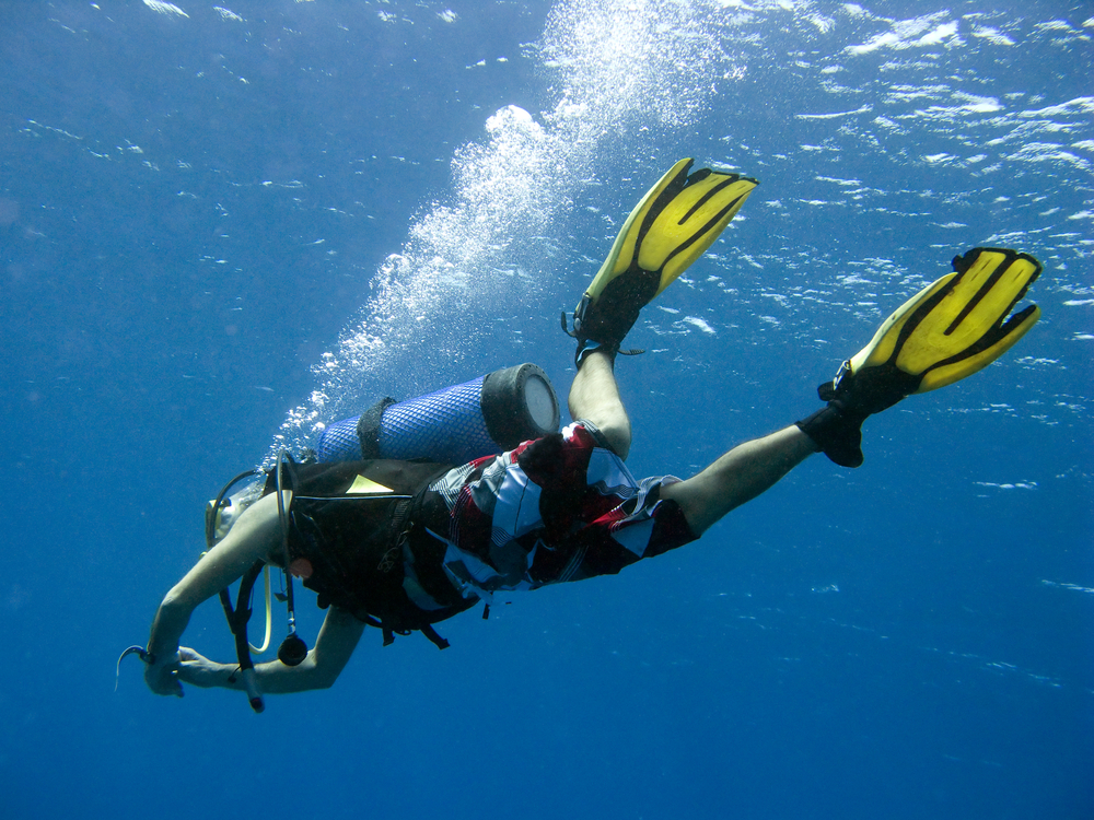 Male diver performs an unassisted emergency ascent and having some trouble with his diving gear