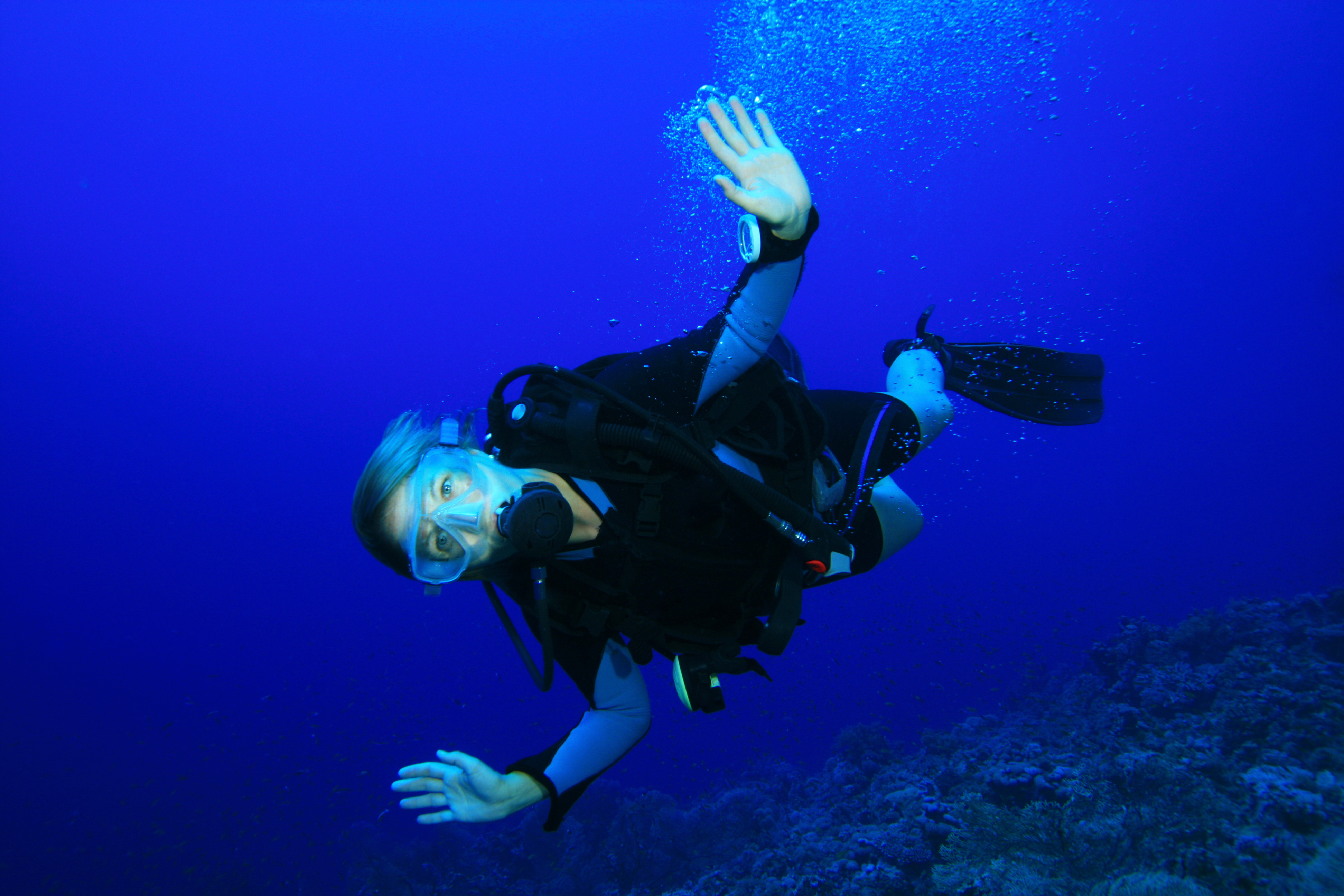 Female diver holds her hands out to each side and enjoys the thrill of flying that drift diving provides her