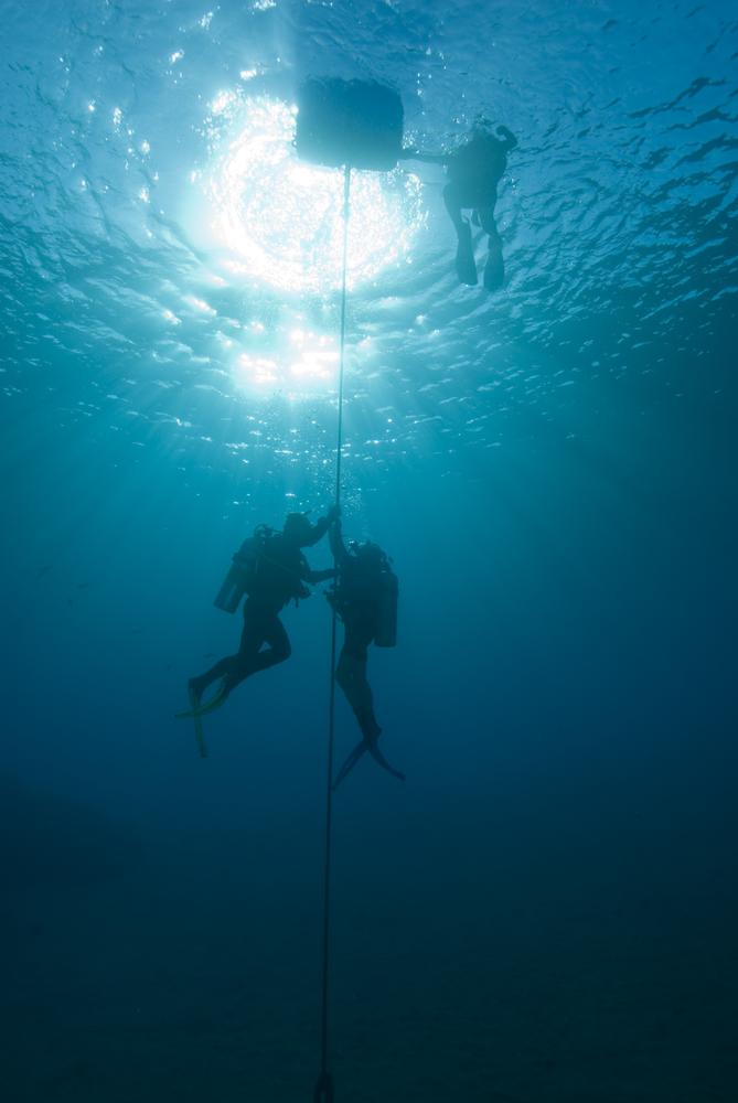 Several recreational divers complete their safety stop at 20 feet directly below the dive boat