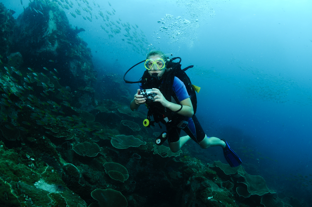 Female diver practices her underwater photography skills on an exciting photo expedition in the warm waters of Caribbean