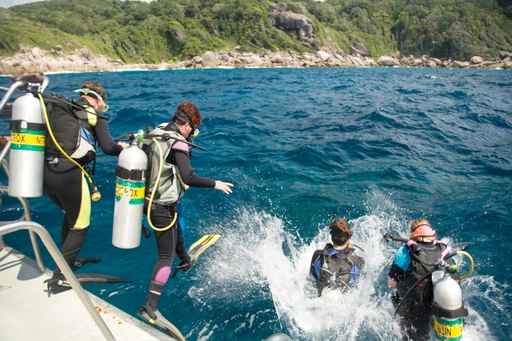 liveaboard dive instructor teaching dive students how to perform giant stride entry