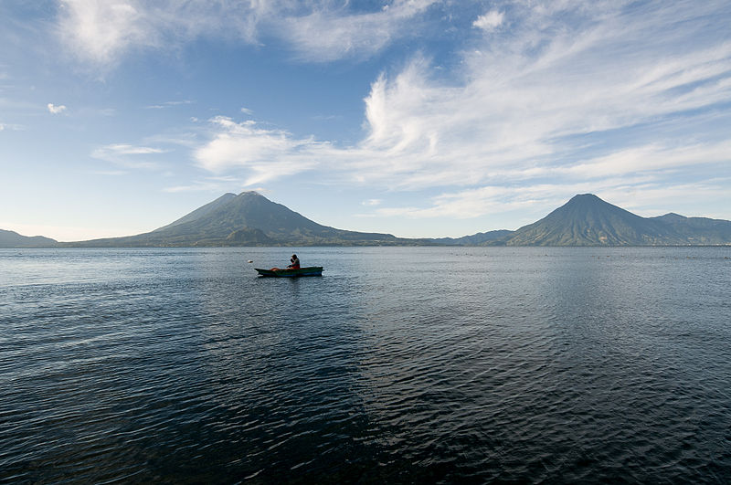 Native guatemalan makes his way across Lake Atitlan using a wooden canoe